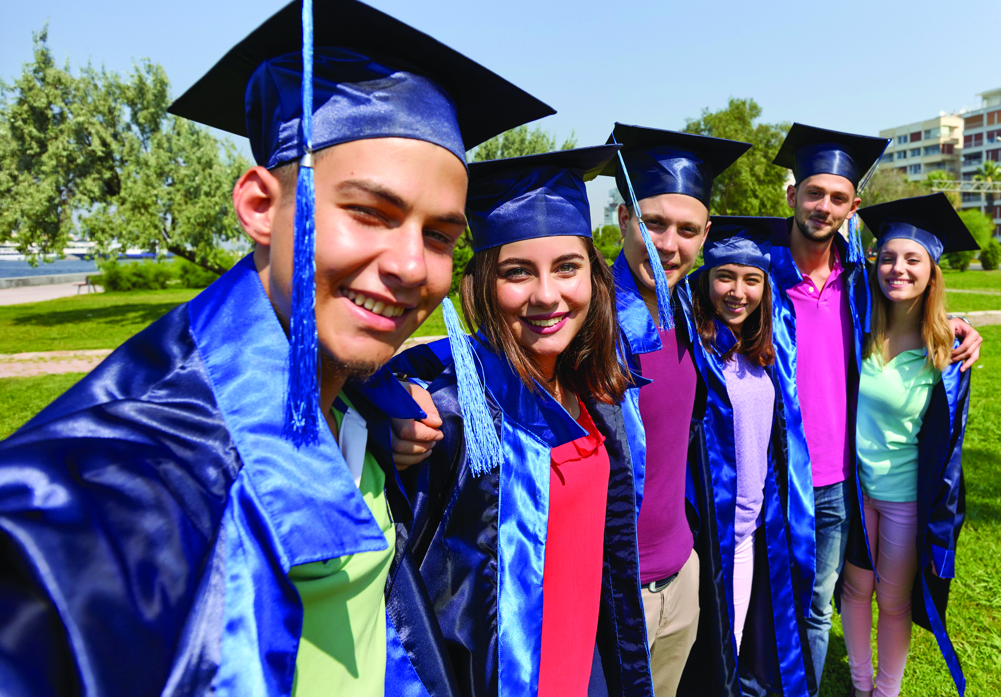 View of students in graduation gown holding diplomas
